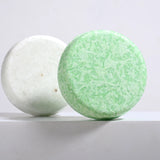 Two bath bombs, one white and one green, on a light gray background