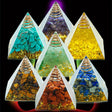 Pyramid-shaped crystal containers with colorful stones inside on a black background