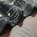 Black fabric with white star and moon pattern on a wooden surface