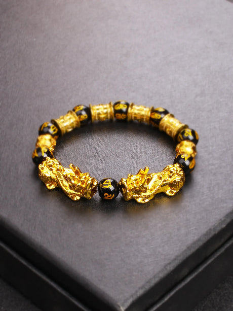 Gold and black beaded bracelet on a gray surface