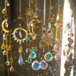Decorative hanging ornaments with crystals and celestial designs on a reflective surface.