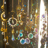 Decorative hanging ornaments with crystals and celestial designs on a reflective surface.