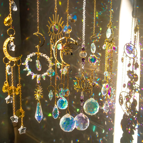 Decorative hanging ornaments with crystals and celestial designs on a reflective surface.