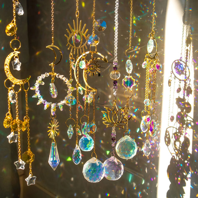 Decorative hanging ornaments with crystals and celestial designs on a reflective surface.