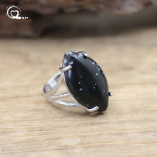 Silver ring with a large black stone on a wooden surface