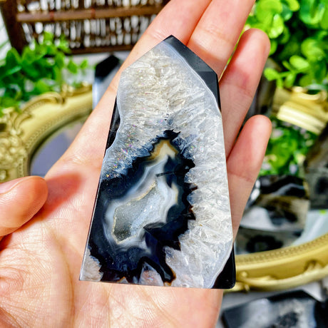Hand holding a polished agate stone with a blurred decorative background