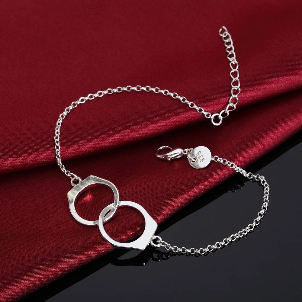Silver bracelet with interlocking rings on a red fabric background