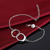 Silver bracelet with interlocking rings on a red fabric background