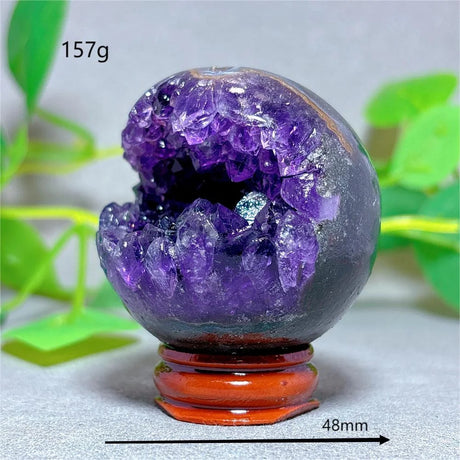 Amethyst crystal sphere with a wooden base on a light background