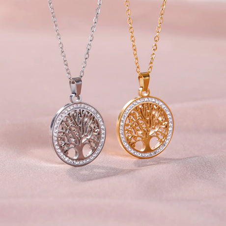 Two tree-shaped pendants, one silver and one gold, on a soft pink background.