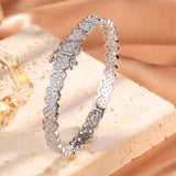 Silver bracelet with heart-shaped links on a beige stone surface