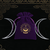 Purple velvet drawstring bag with gold emblem on a black background with white crescent moons.