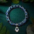 Bracelet with blue and black beaded design and Hamsa charm on a green fabric background