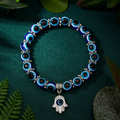 Bracelet with blue and black beaded design and Hamsa charm on a green fabric background