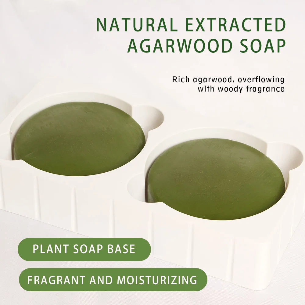Two green agarwood soaps in white containers with text describing the product.
