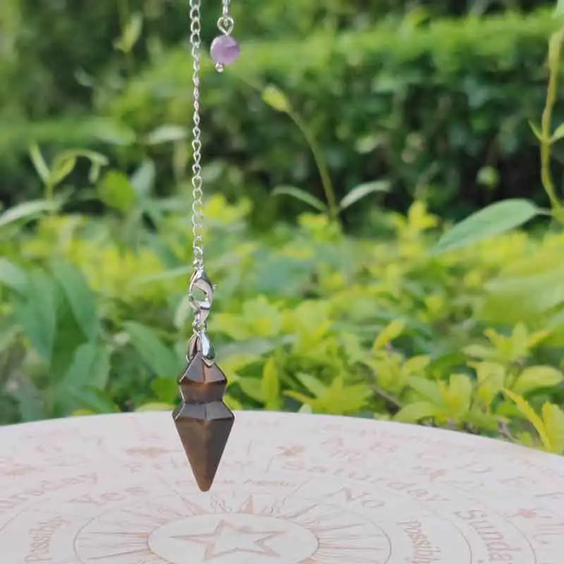 Pendulum with a purple bead on a green leafy background
