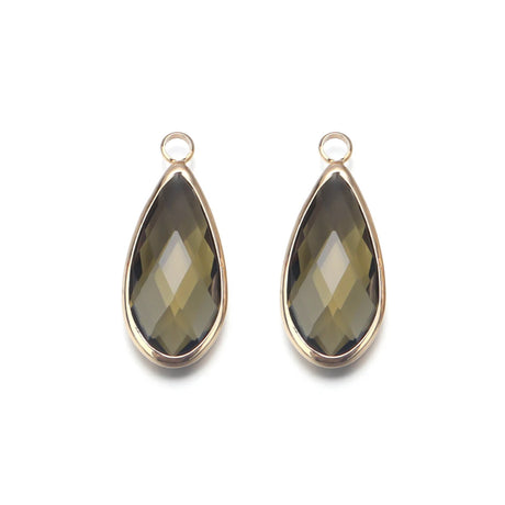 Two teardrop-shaped gemstones with gold settings on a white background