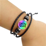 Black braided leather bracelet with a colorful beaded charm on a wrist against a white background