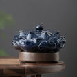 Blue ceramic incense burner shaped like a lotus flower on a wooden surface with a dark background