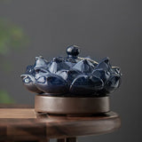 Blue ceramic incense burner shaped like a lotus flower on a wooden surface with a dark background