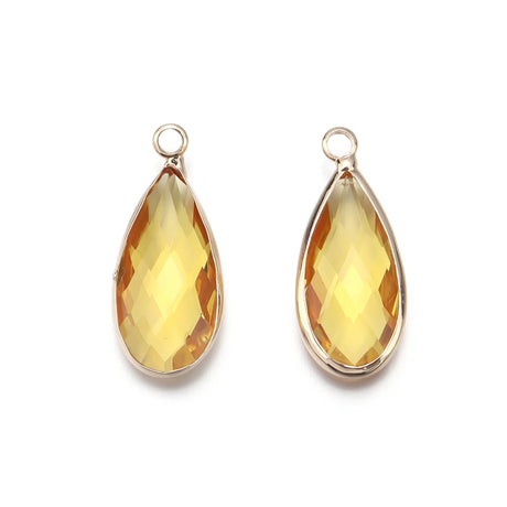Teardrop-shaped yellow gemstones on gold prongs against a white background