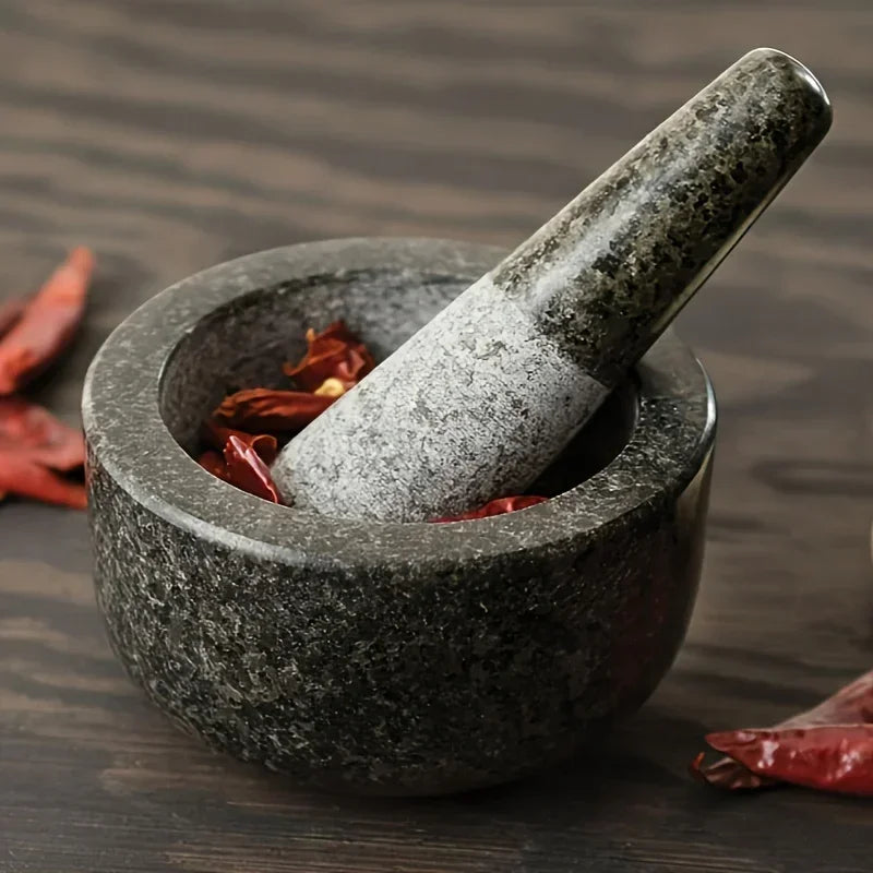 Mortar and pestle with dried red chilies on a wooden surface