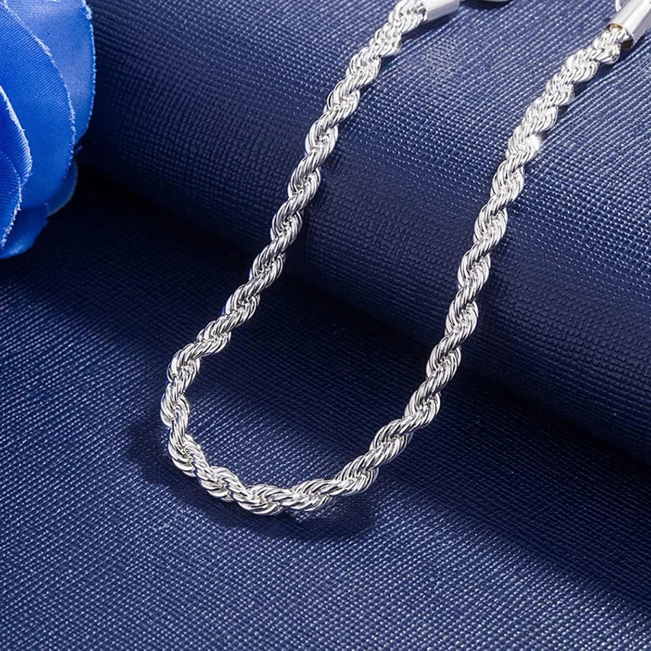 Silver rope chain necklace on a blue fabric background