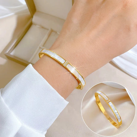 Gold bracelet with white stone on a wrist, close-up view.