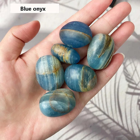 Hand holding blue onyx stones with a blurred background