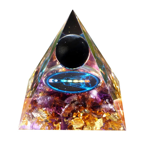 Triangular crystal pyramid with colorful stones and a black sphere on a white background