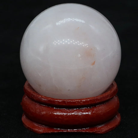 White crystal ball on a red stand against a black background