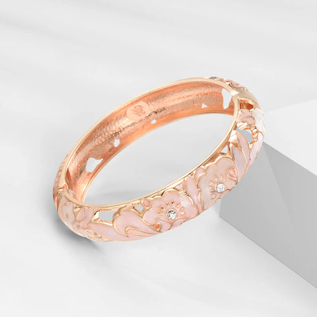 Rose gold bracelet with floral designs on a light gray background