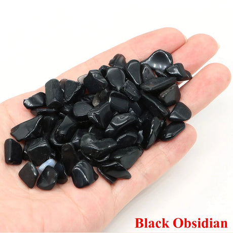Hand holding black obsidian stones with 'Black Obsidian' text on a white background