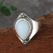 Silver ring with a light blue stone on a wooden surface