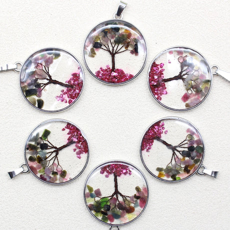 Set of six round pendants with tree designs and pink flowers on a white background
