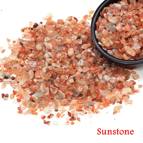 Sunstone crystals with a small bowl filled with them on a white background