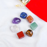 Set of colorful crystals on a white surface with a red drawstring bag in the background.