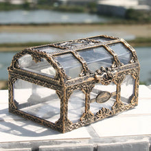 Decorative glass box with ornate metal frame on a marble surface