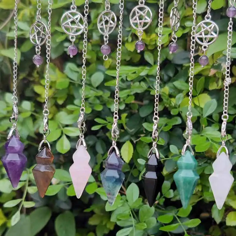 Necklaces with crystal pendants hanging against a green leafy background