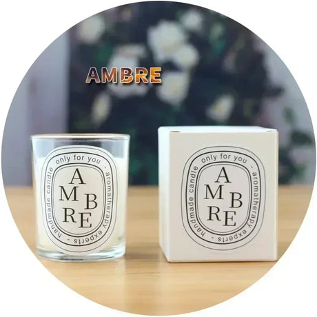 Ambre candle and packaging on a wooden surface with a blurred floral background