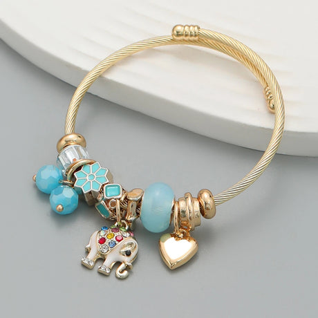 Gold bracelet with colorful charms on a gray surface