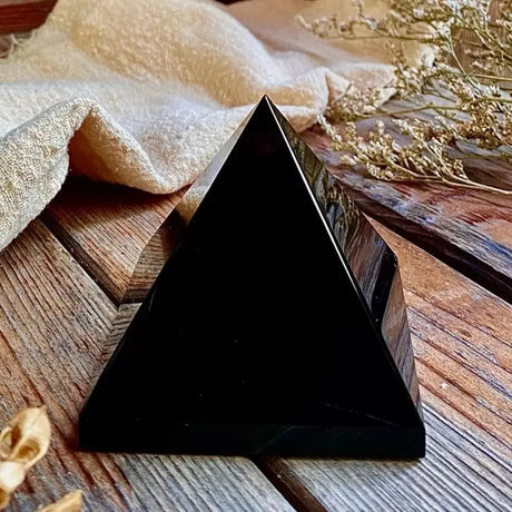 Black triangular stone on a wooden surface with dried plants