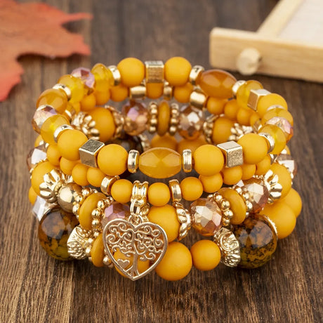 Stack of yellow beaded bracelets with gold accents on a wooden surface