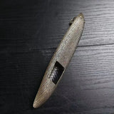Bronze-colored metal object on a dark wooden surface