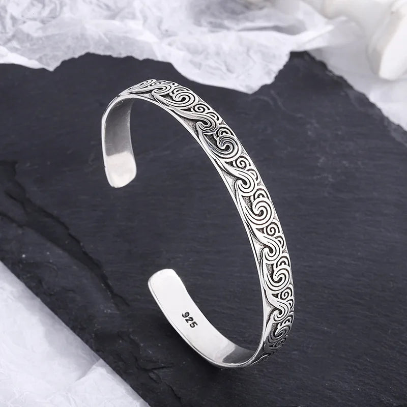 Silver bracelet with intricate patterns on a dark surface