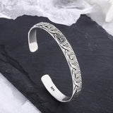 Silver bracelet with intricate patterns on a dark surface
