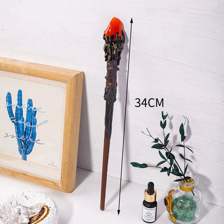 Decorative staff with red top, framed artwork, and small plants on a white surface