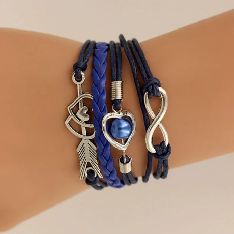 Set of three bracelets with charms on a wrist against a beige background