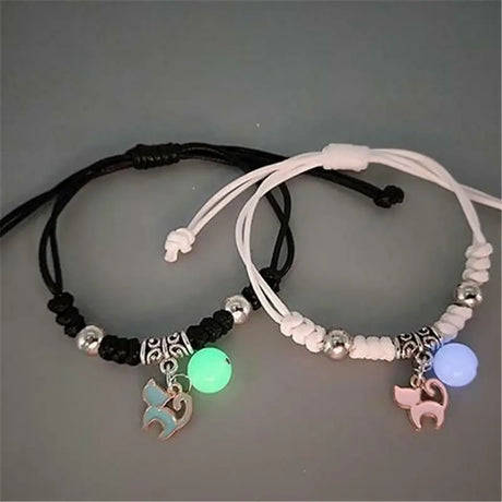 Two bracelets with glowing charms on a gray background