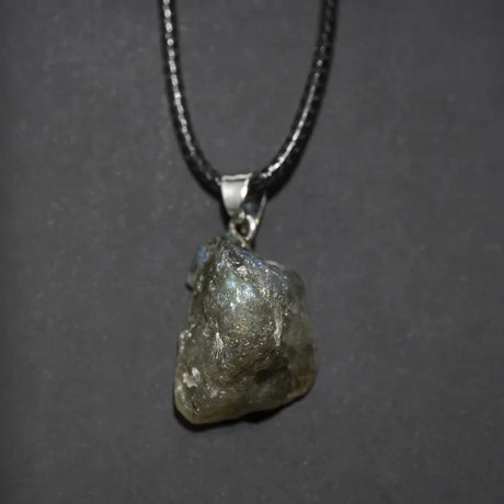 Raw diamond pendant on a chain against a dark background